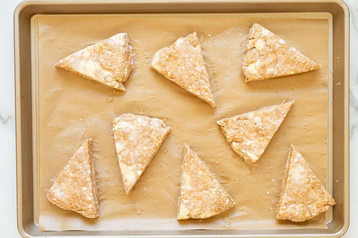 Cut up and unbaked scones on a baking sheet.