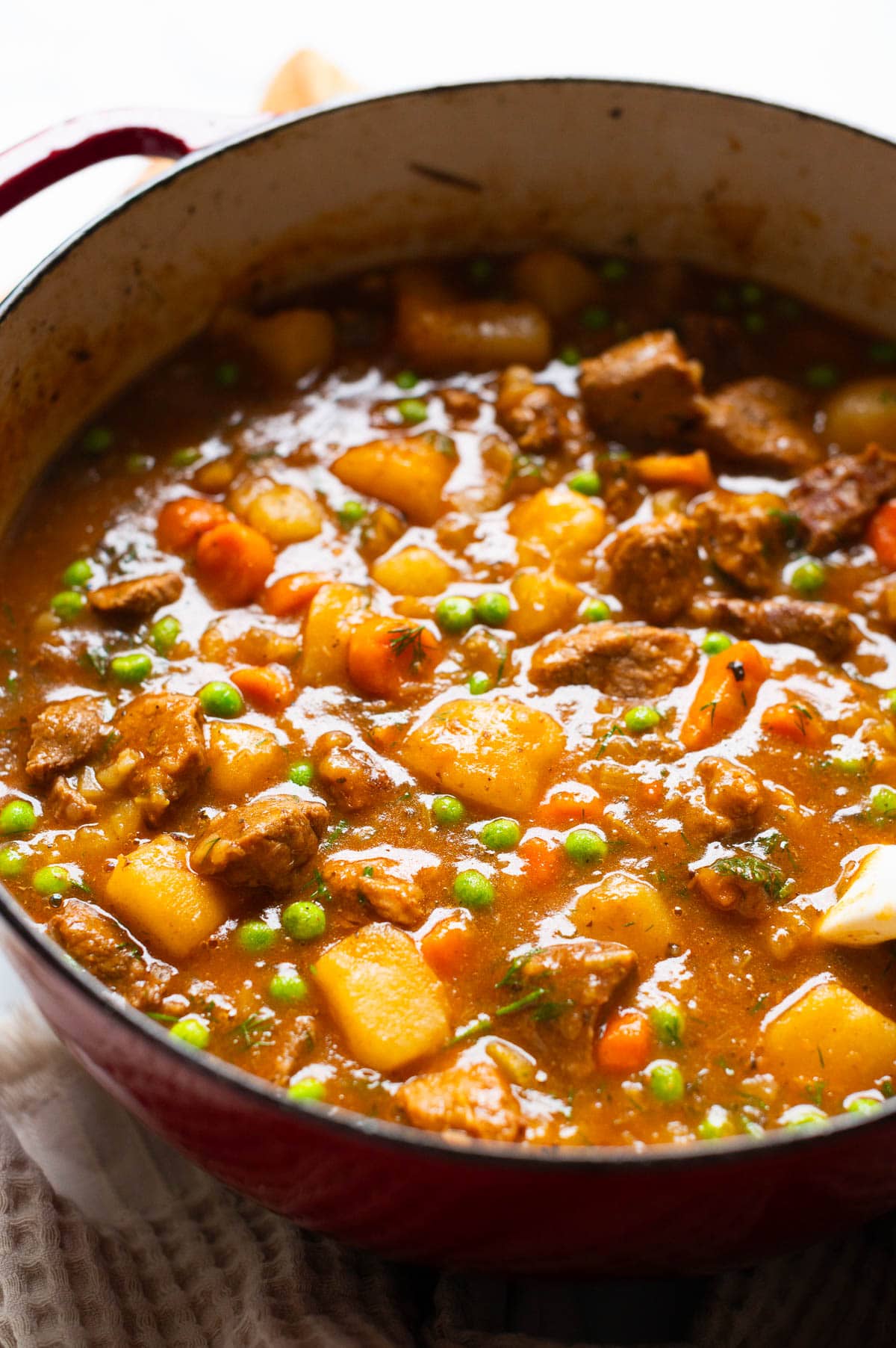 Side view of beef stew in red pot.