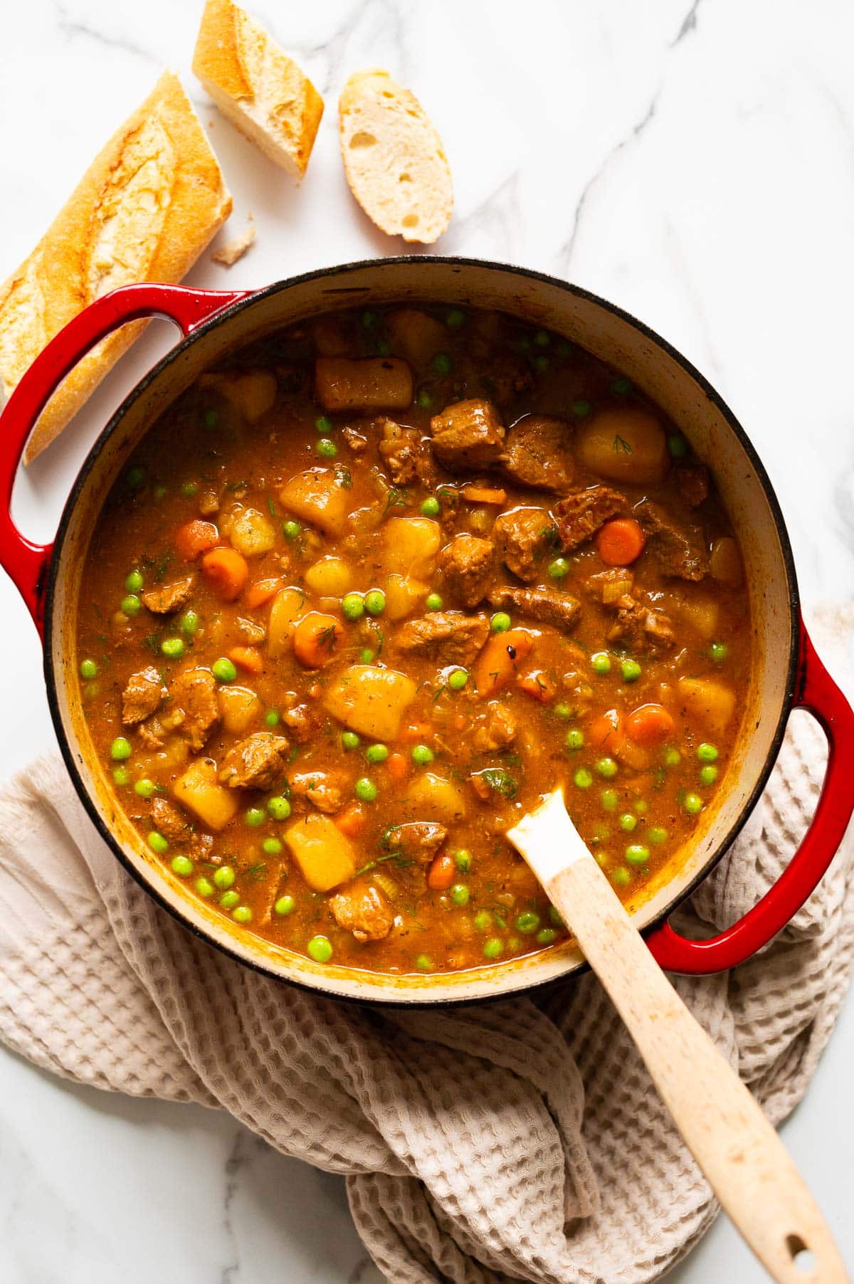 Beef stew in a pot with wooden spoon.