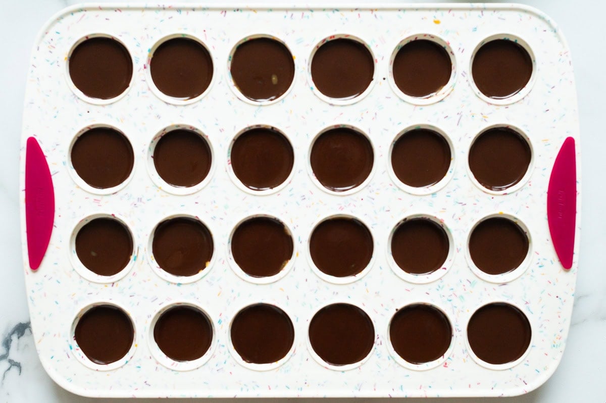 Assembled peanut butter cups in a silicone mini muffin tin.