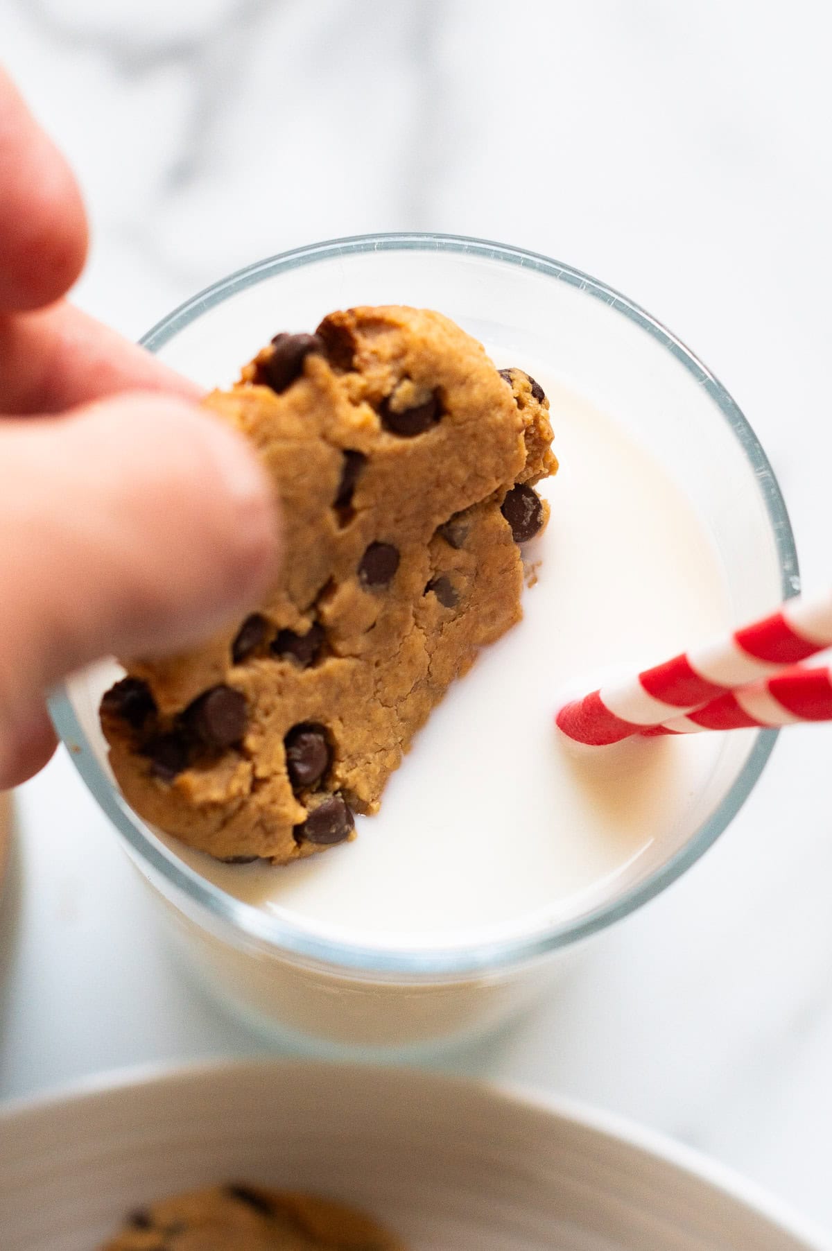 Person dunking a cookie into a glass with milk.