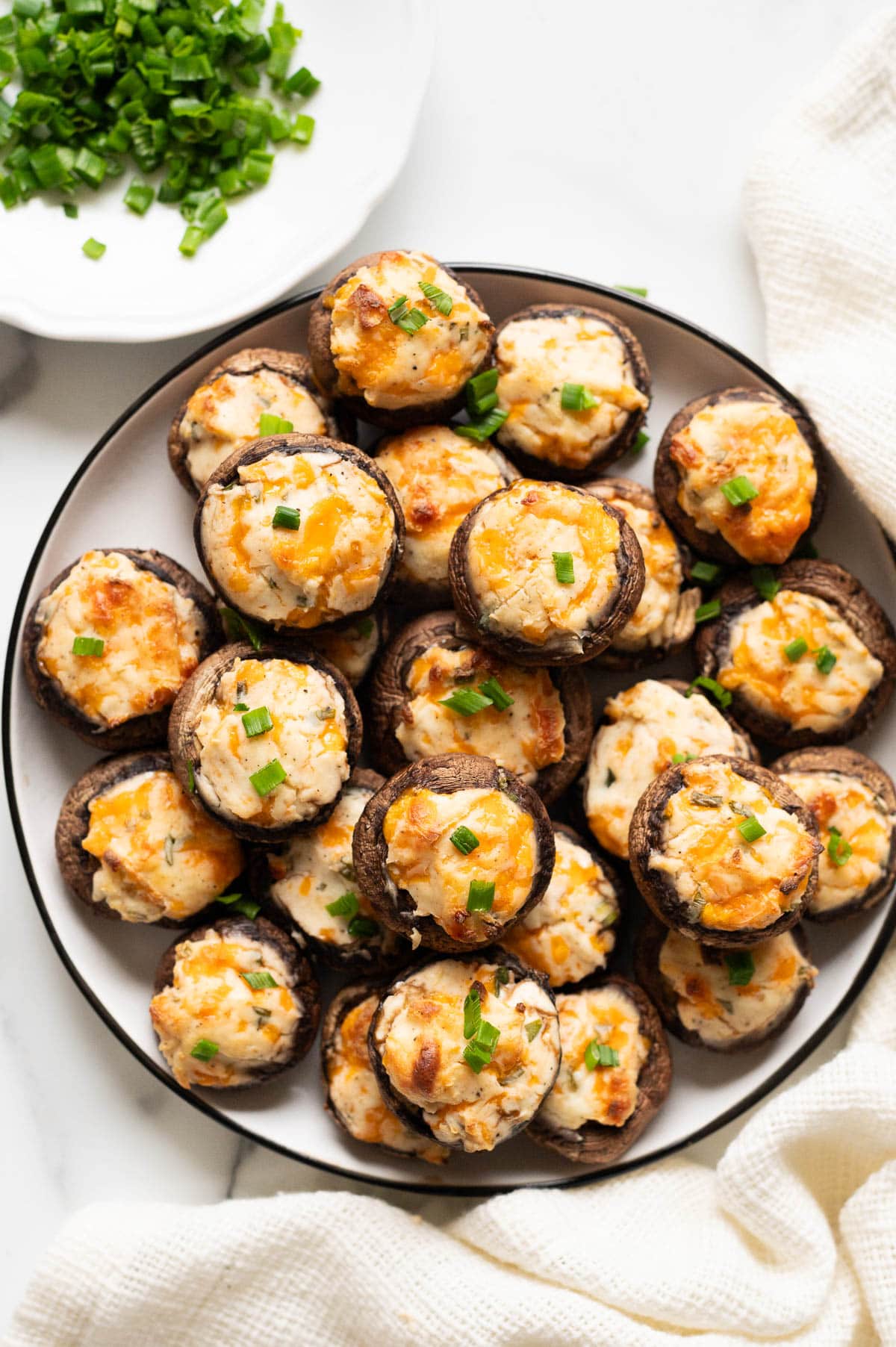 Cream cheese stuffed mushrooms garnished with chives on a plate.