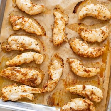 Baked chicken tenders on a baking sheet.