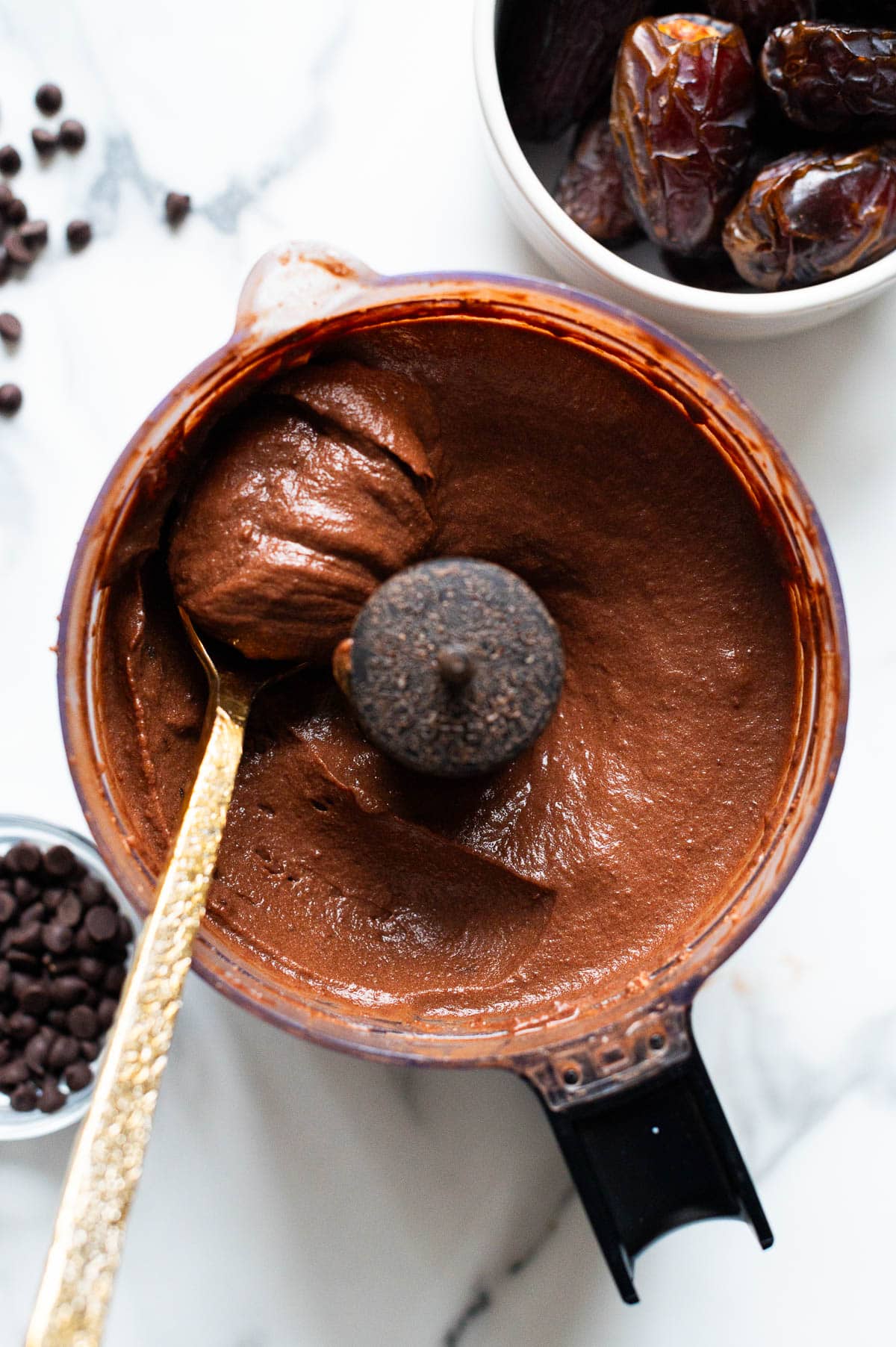 Hard boiled egg chocolate pudding in a food processor bowl scooped with a spoon.