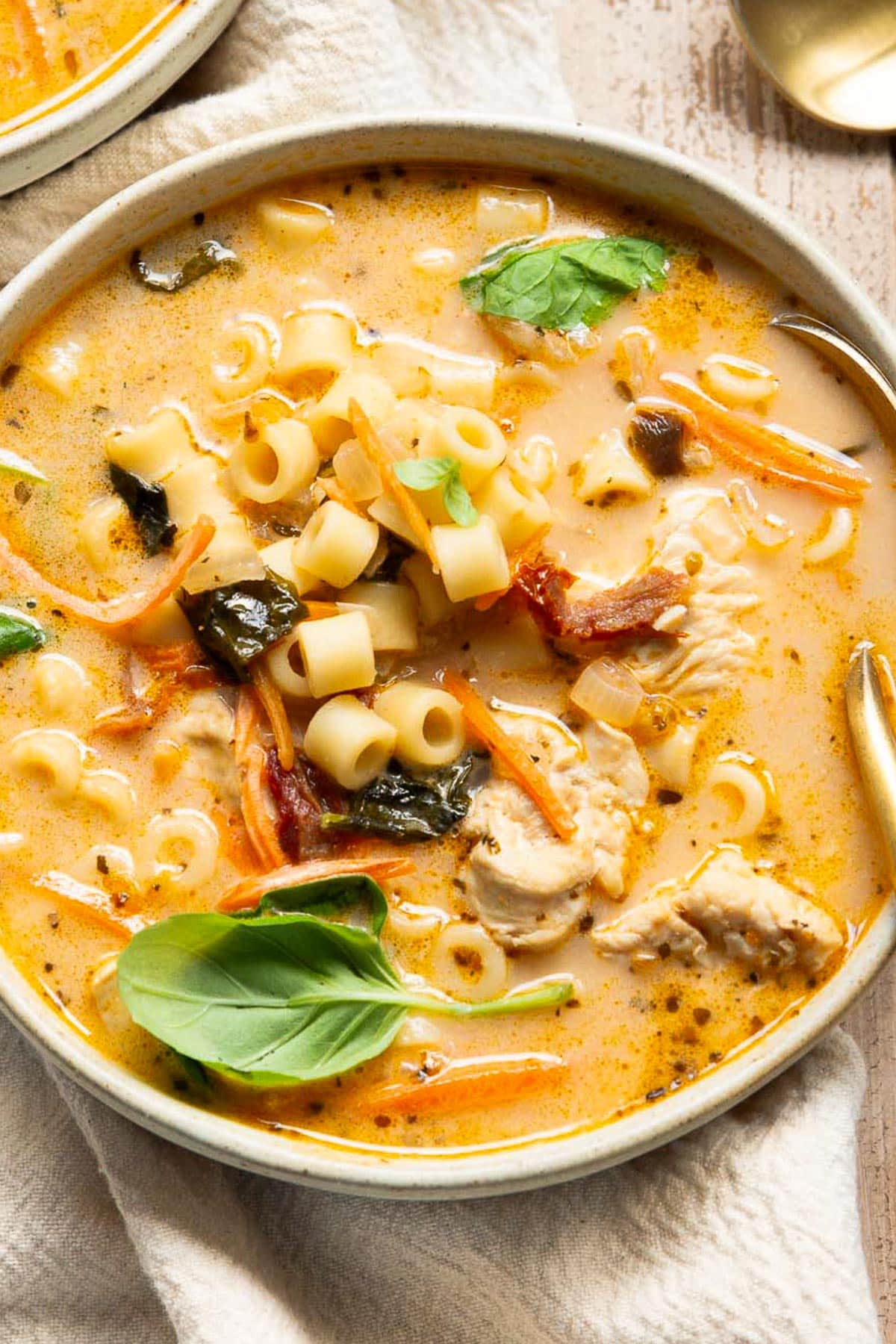 Marry me chicken soup garnished with basil in a bowl with spoon.