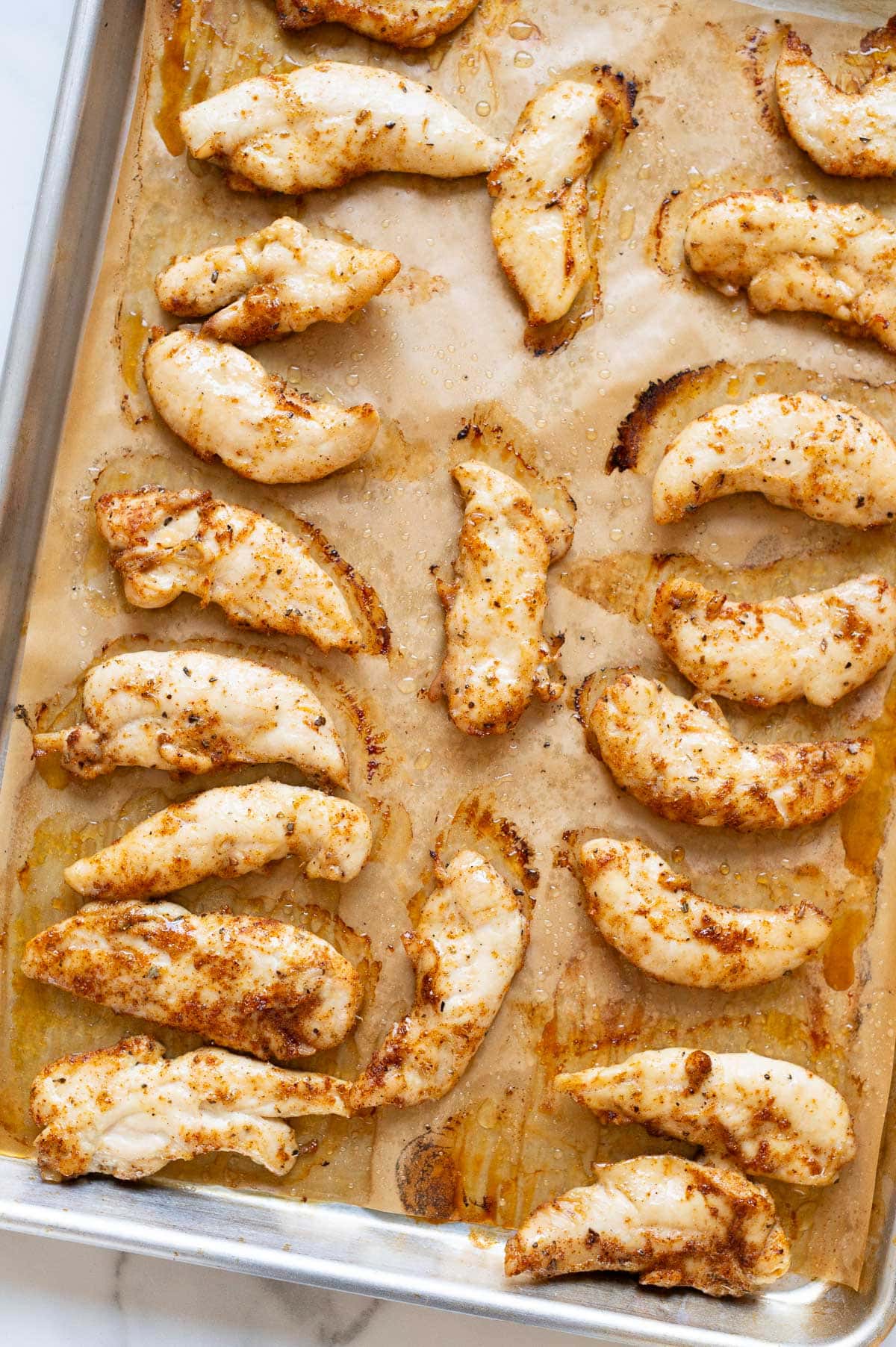 Baked chicken tenders on a baking sheet.