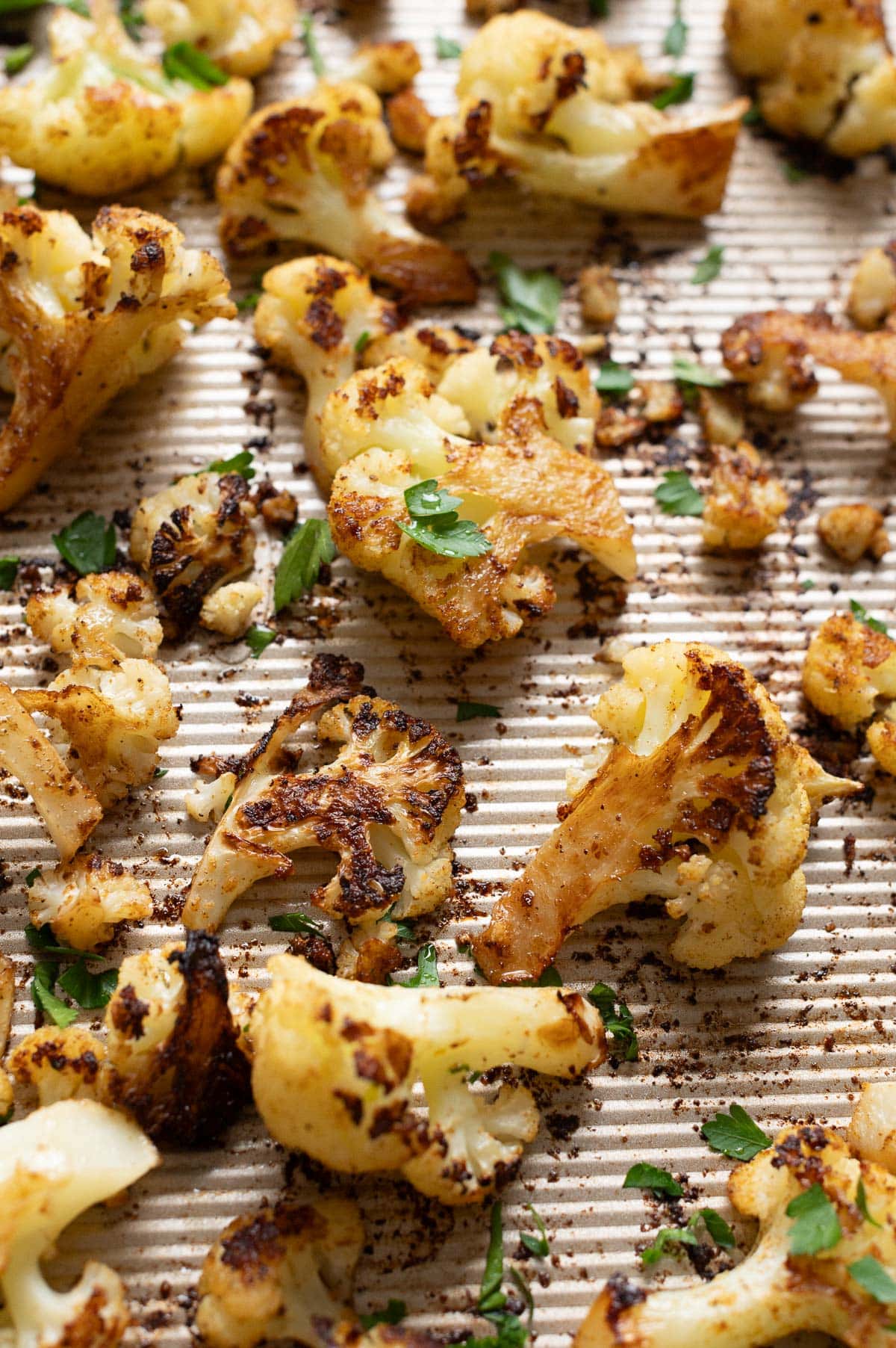 Roasted cauliflower garnished with parsley on a baking sheet.