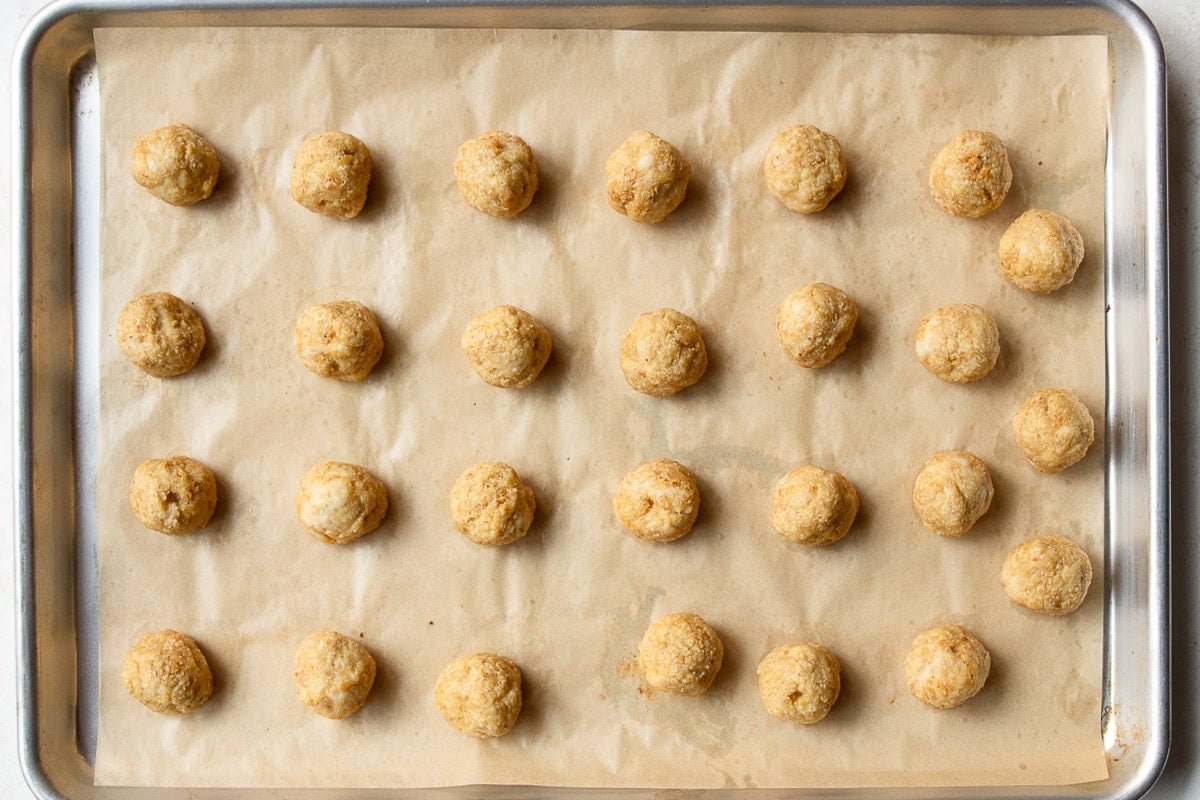 Baked chicken meatballs on parchment paper lined baking sheet.