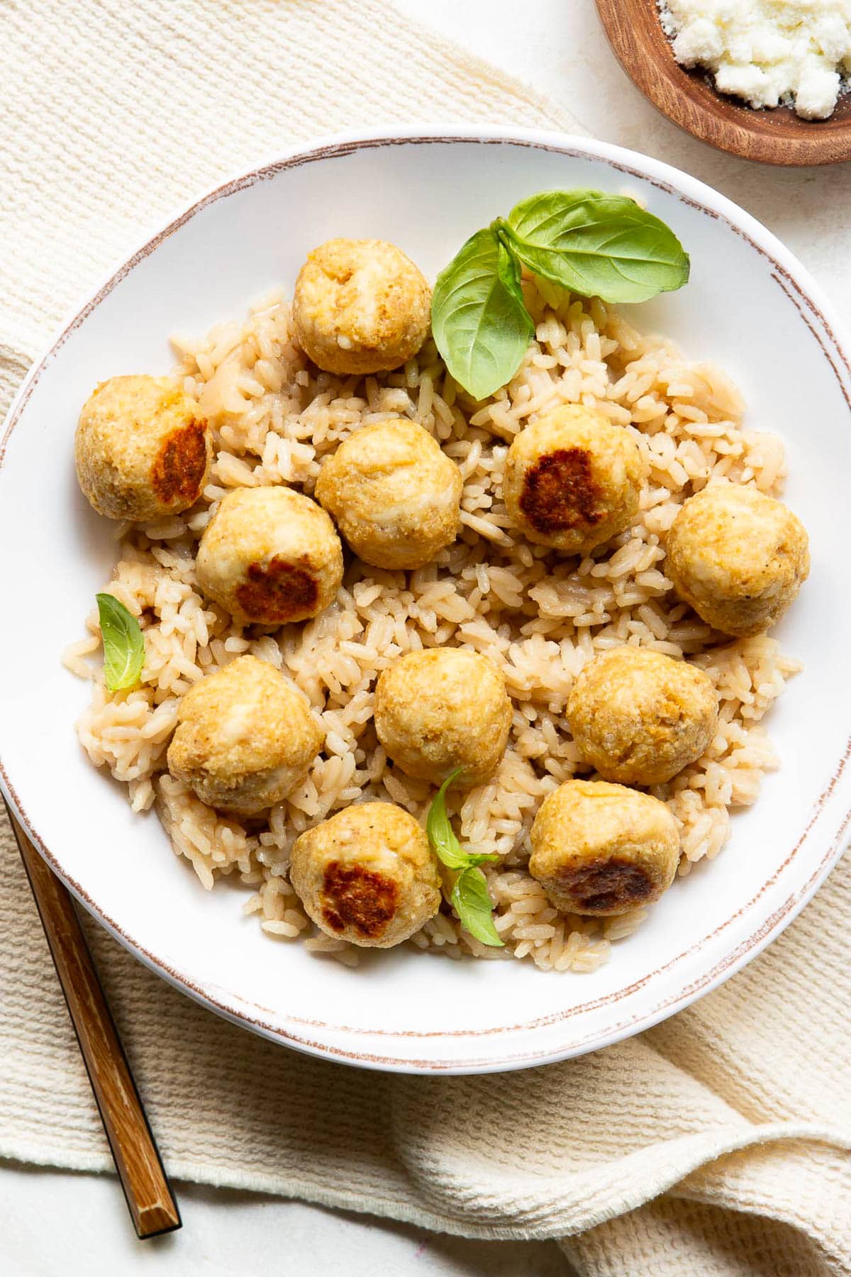 Chicken meatballs served over brown rice and garnished with basil.