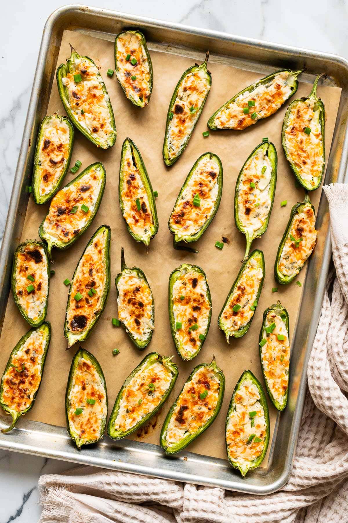 Cream cheese stuffed jalapeno peppers on a baking sheet.