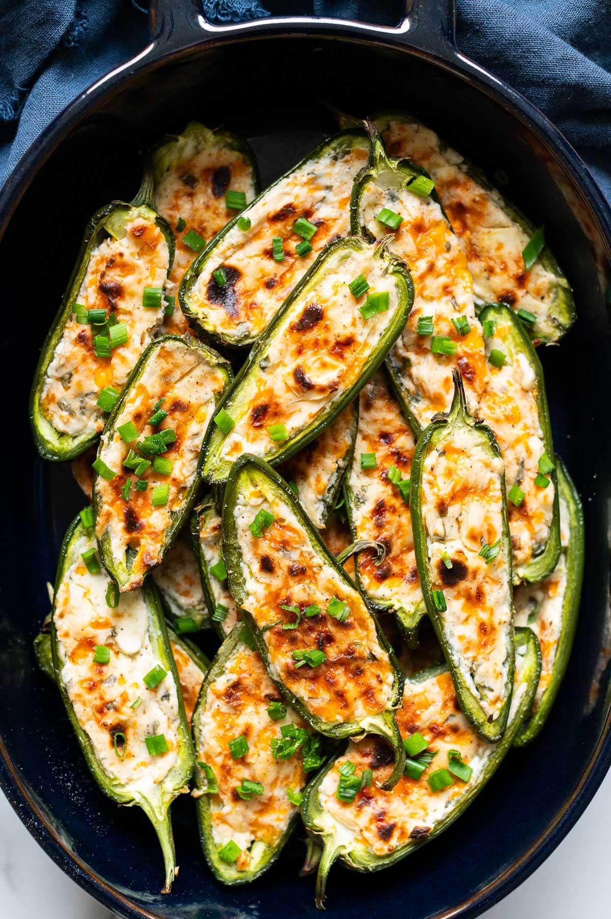 Cream cheese stuffed jalapeno peppers in a baking dish.