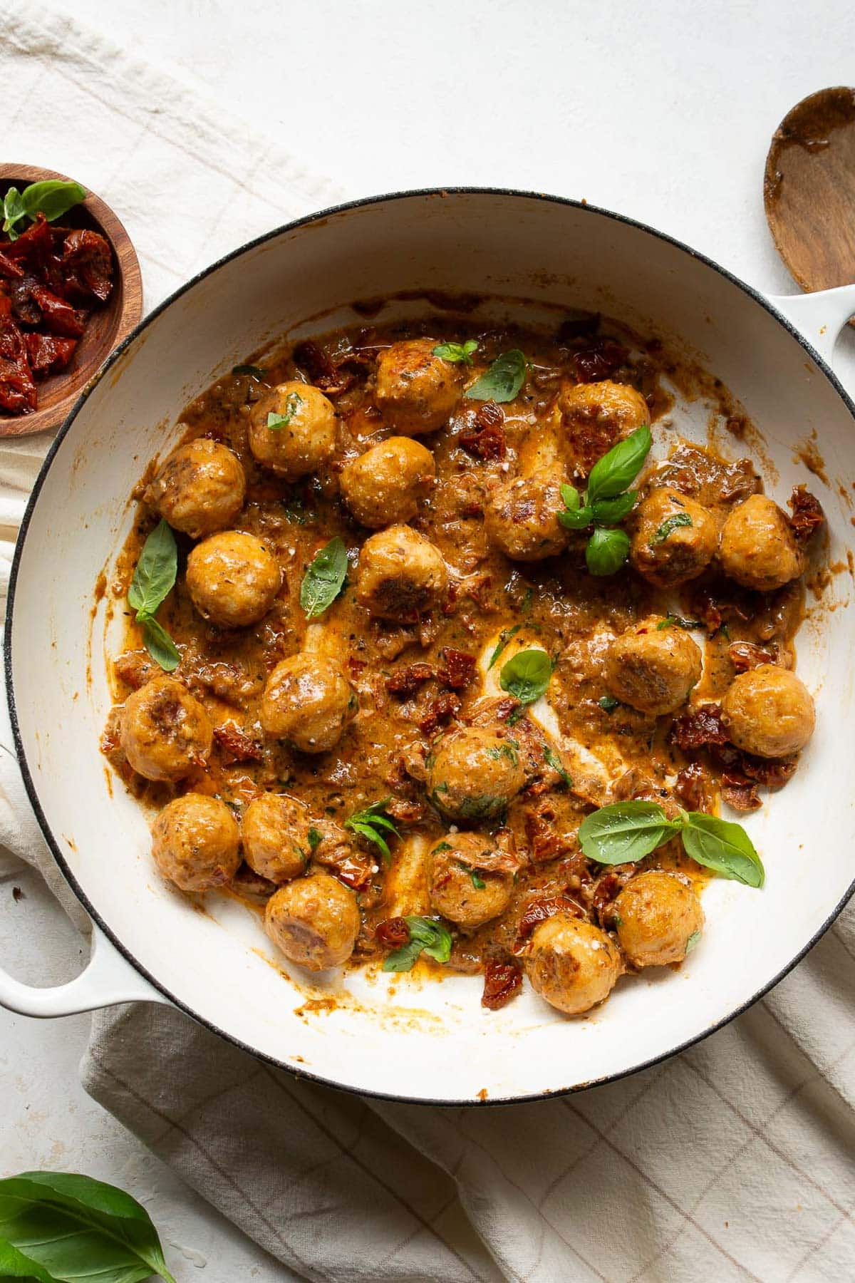 Marry me chicken meatballs garnished with basil in a skillet.