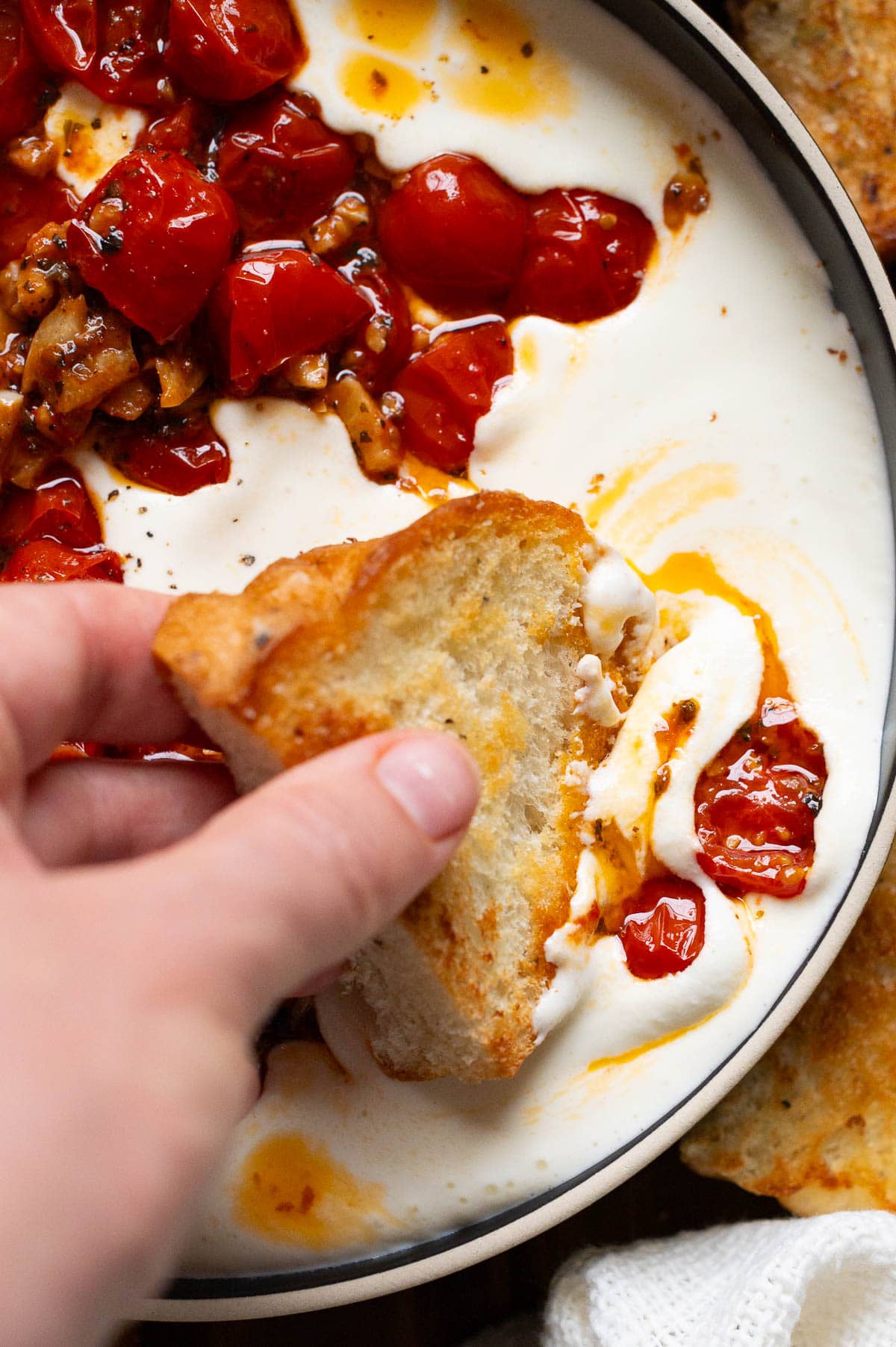 Person dipping a slice of bread into whipped feta dip.