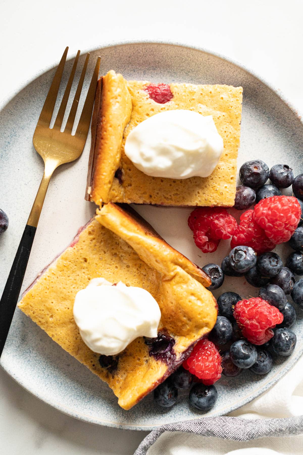 Two slices of baked cottage cheese with Greek yogurt and berries on a plate.