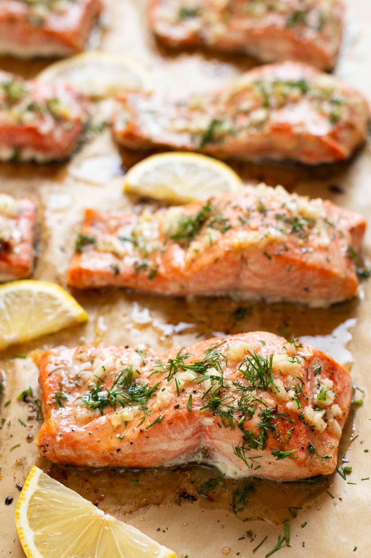 Baked salmon garnished with dill and lemon on a baking sheet.