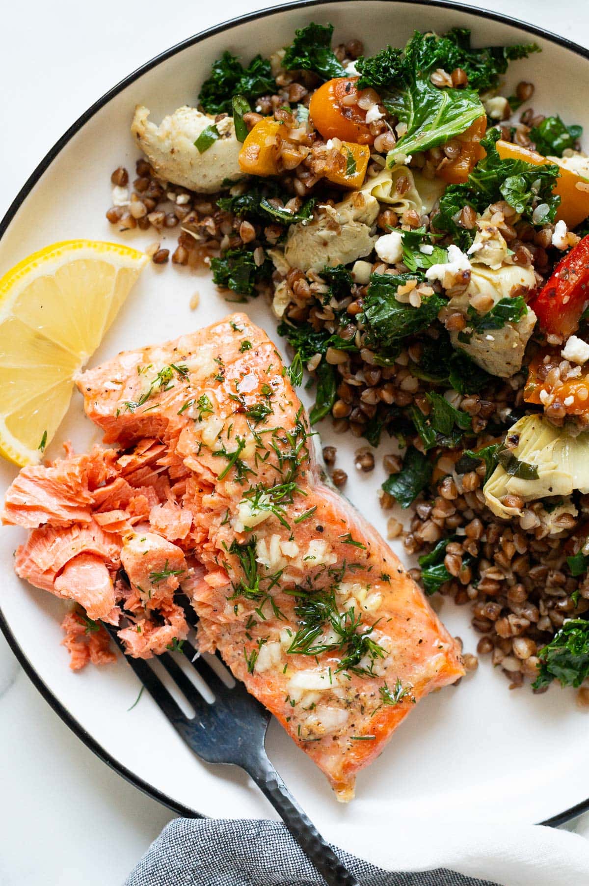 Baked salmon flaked with a fork and served with buckwheat stir fry.