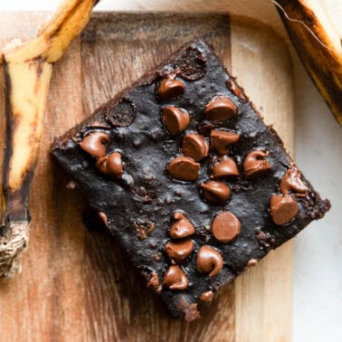 Banana brownie on a cutting board with a banana peel.