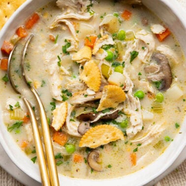 Healthy chicken pot pie soup with crackers in a bowl.