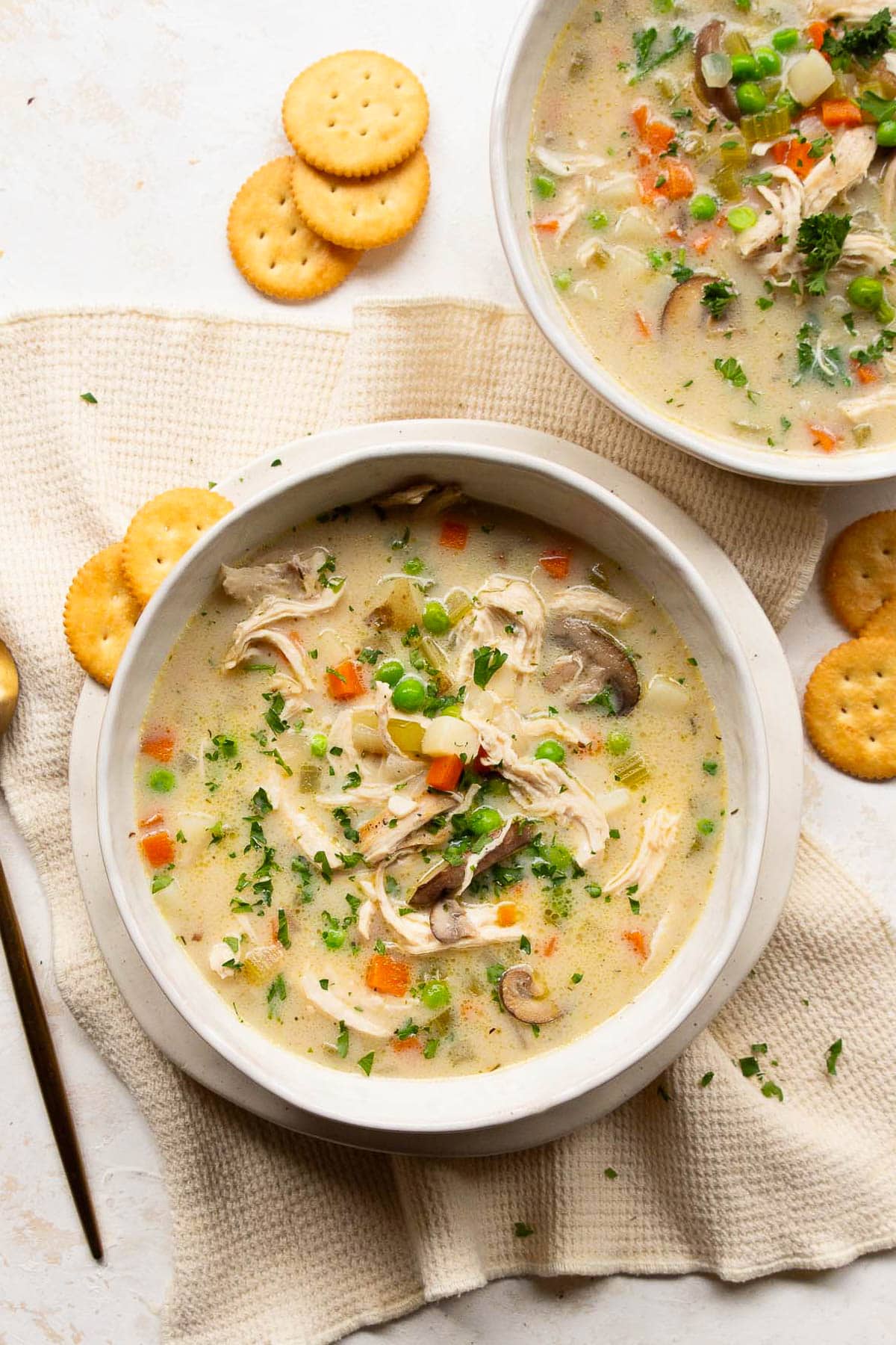 Healthy chicken pot pie soup served in bowls with crackers.