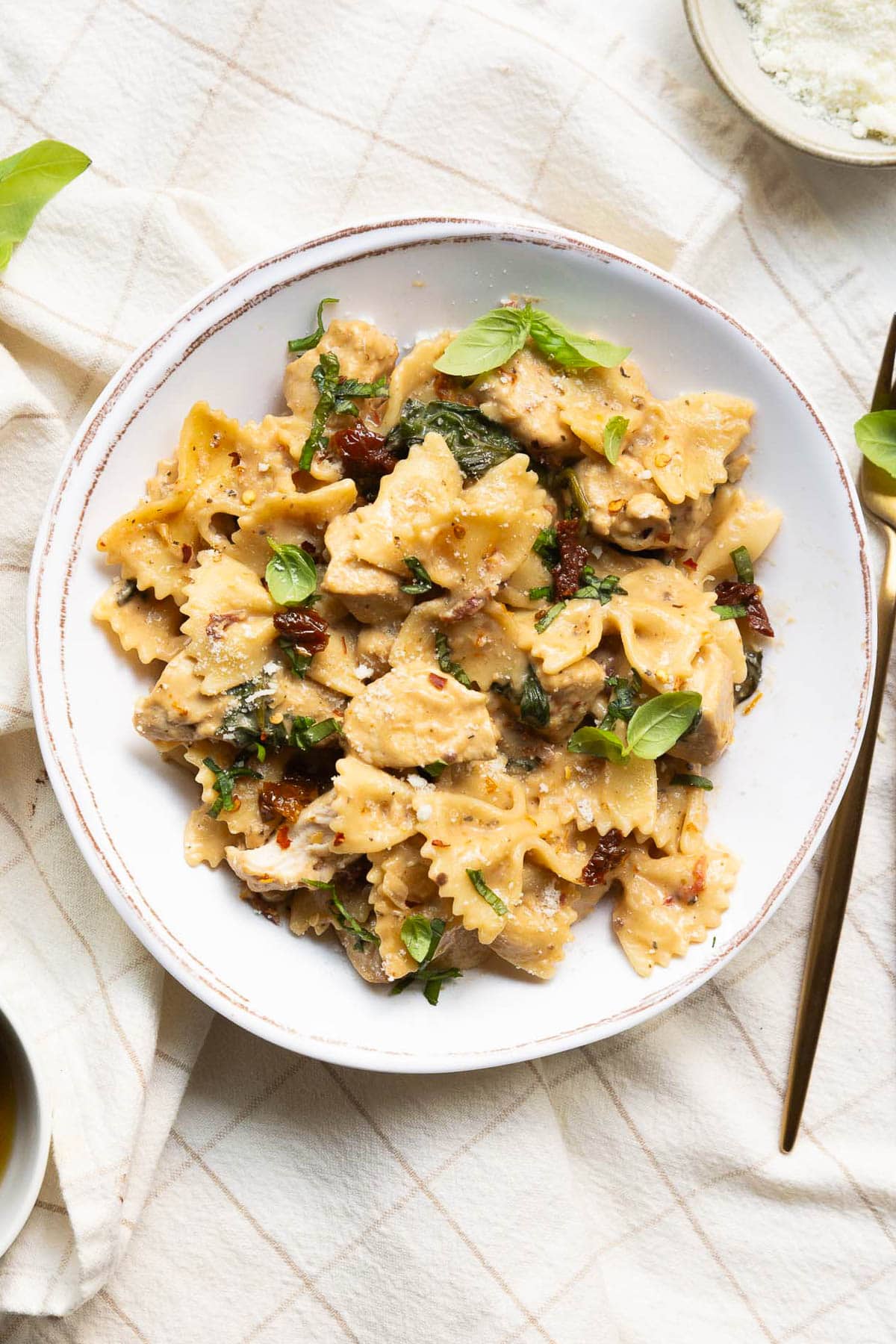 Looking down on a plate with marry me chicken pasta garnished with basil.