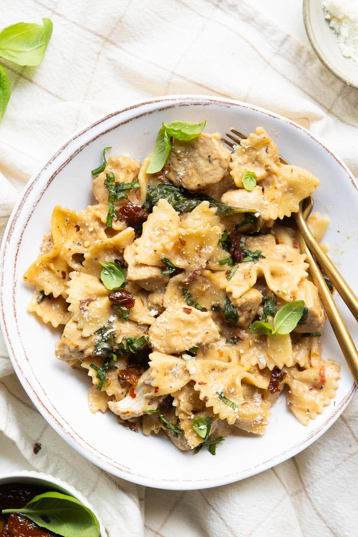 Marry me chicken pasta served on a plate with fork and spoon.