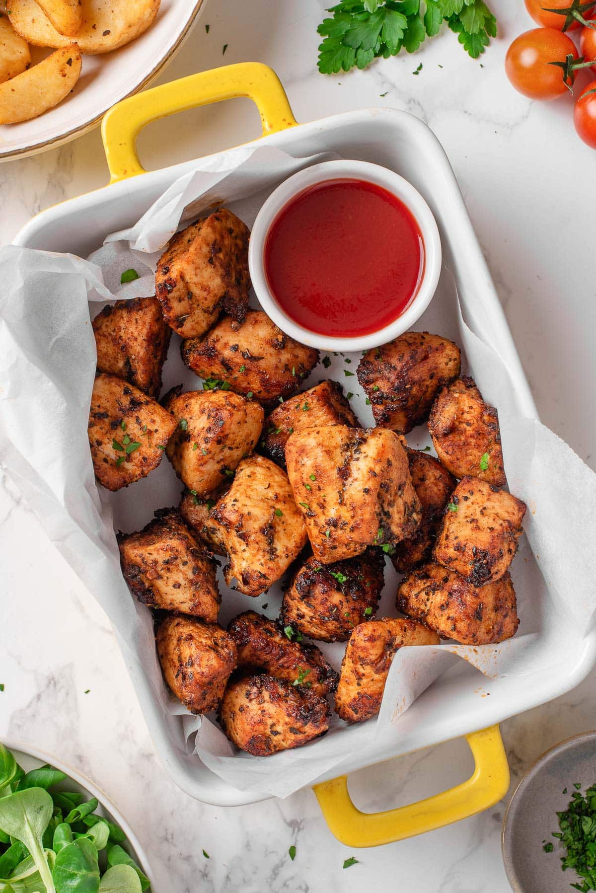 Air fryer chicken bites in a baking dish with the sauce.