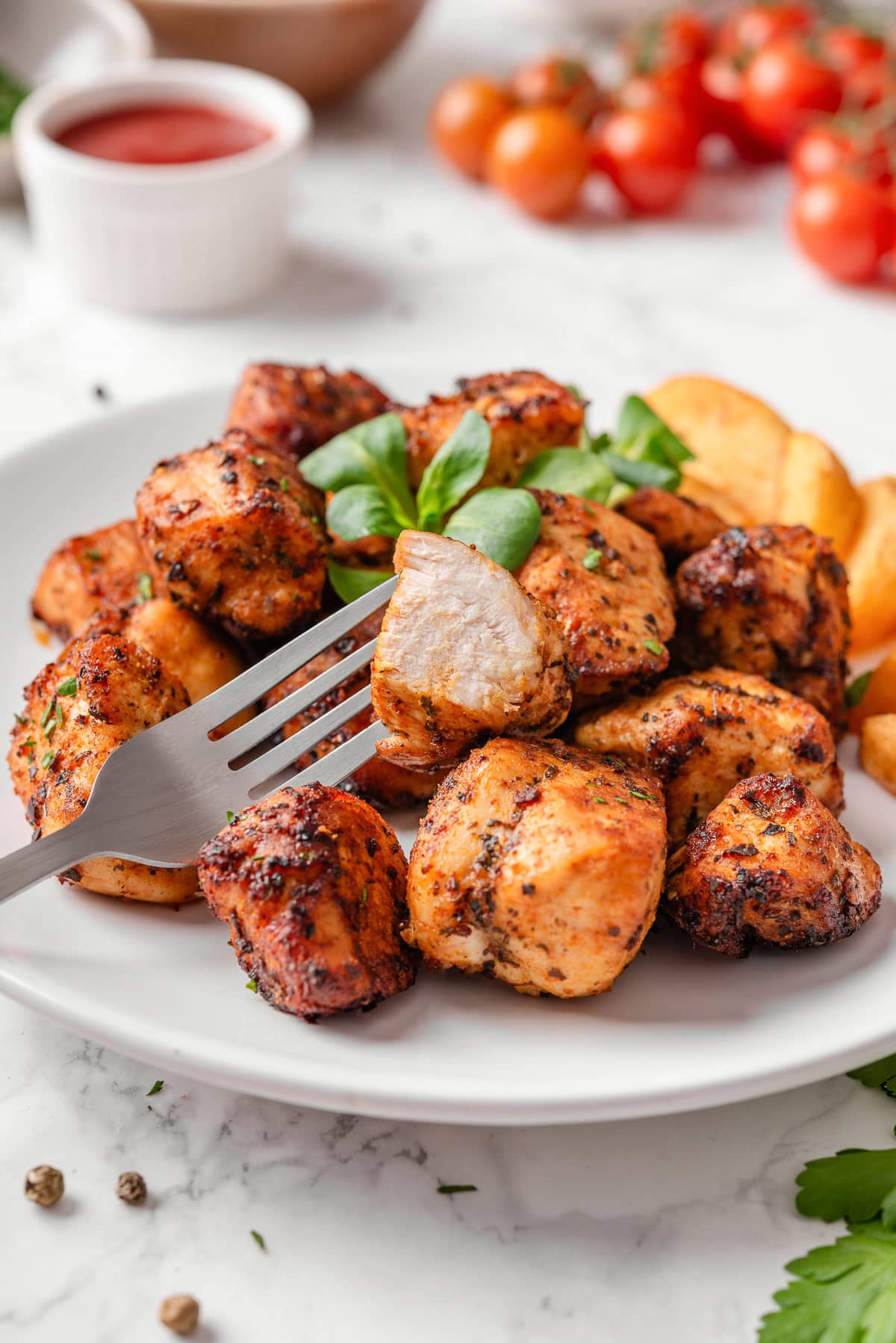 Air fryer chicken bite cut in half on a fork showing texture inside.
