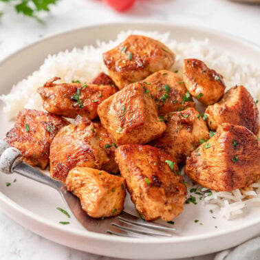 Chicken bites served with rice on a plate.