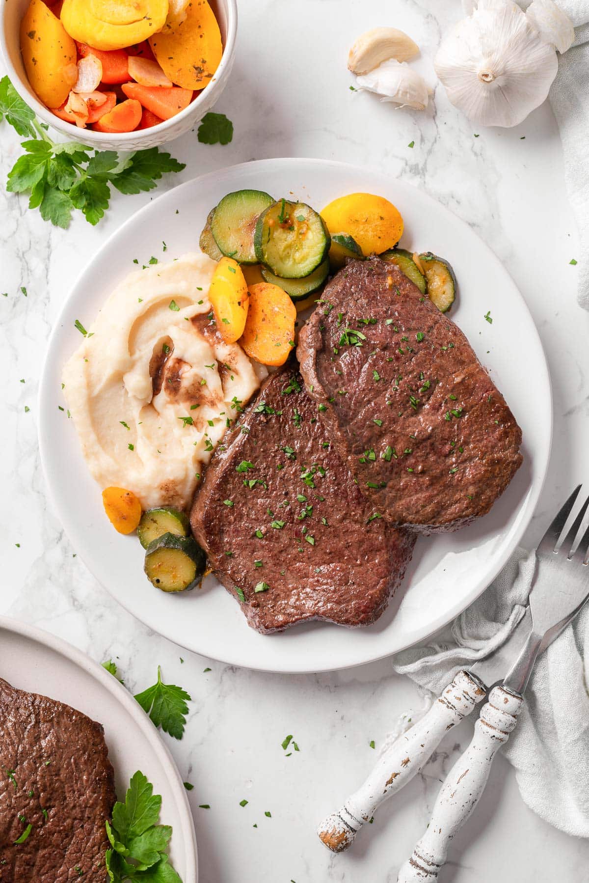 Steaks with mashed potatoes and roasted vegetables on a plate.