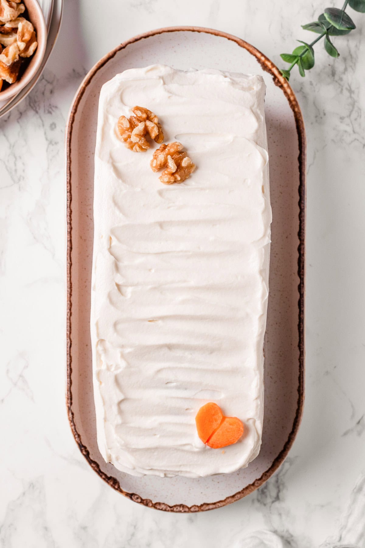 Looking down on carrot cake loaf with cream cheese frosting on a plate.