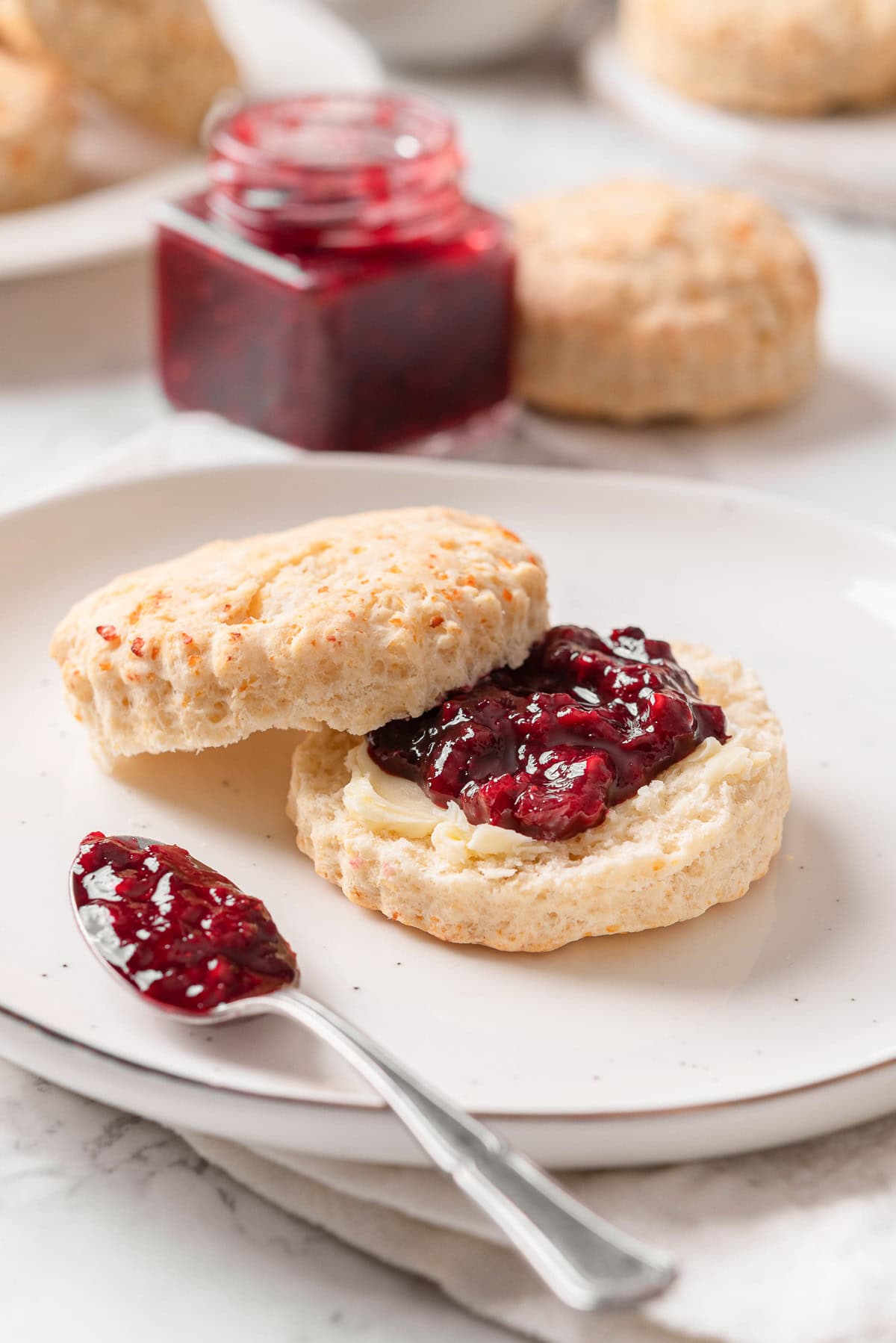 Cottage cheese biscuit cut in half and spread with butter and jam on a plate.
