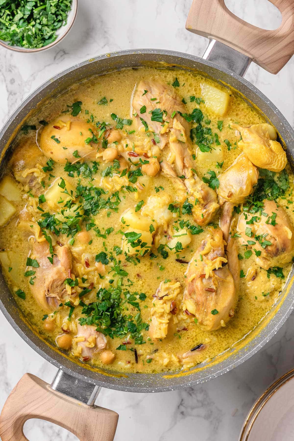 Closeup of curry chicken soup with drumsticks and cilantro in a pot.