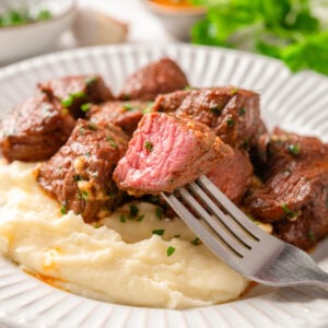Air fryer steak bites on a fork served with mashed potatoes.