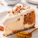 Carrot cake cheesecake slice on a plate with a spoon.