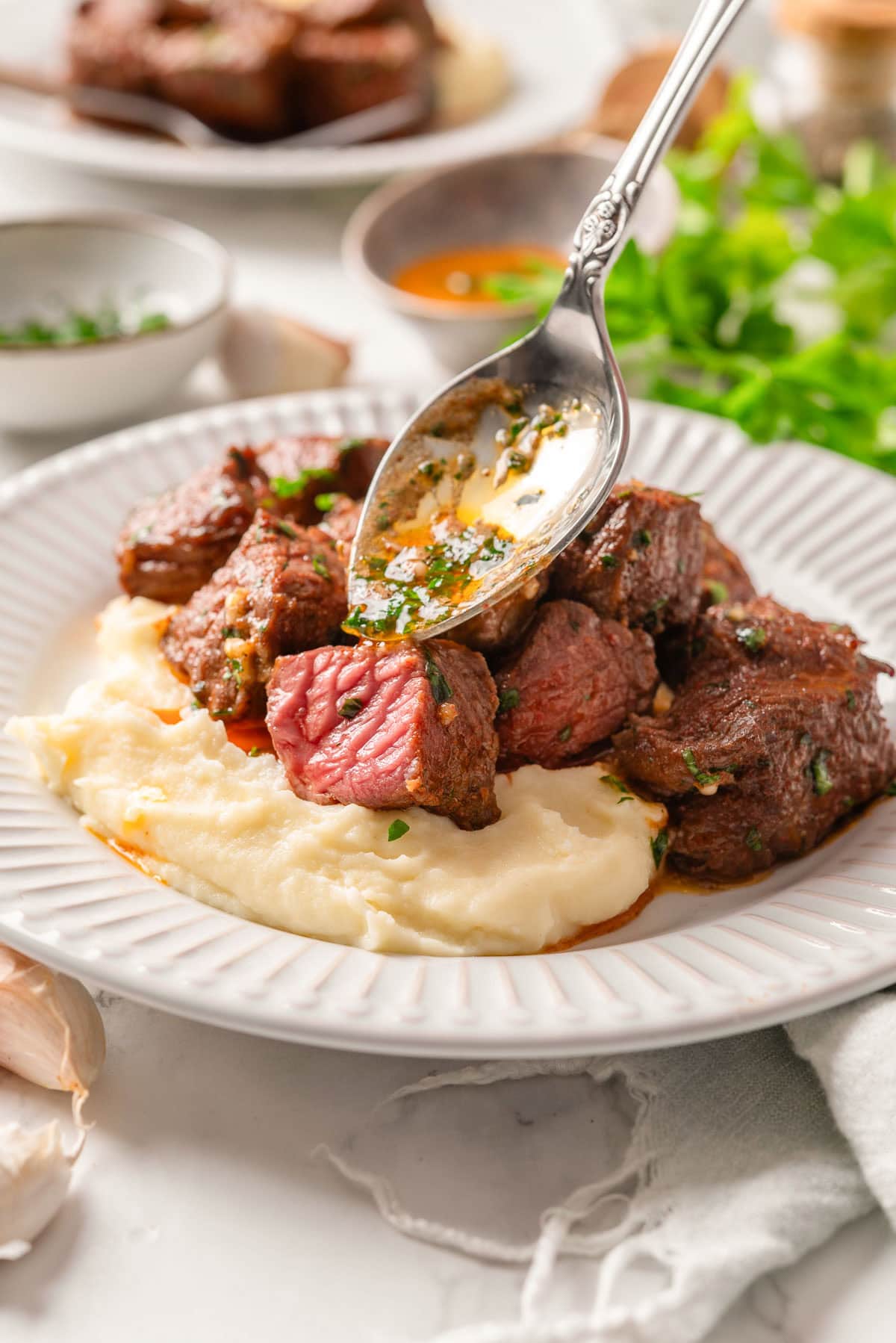 Pouring garlic butter on air fryer steak bites.