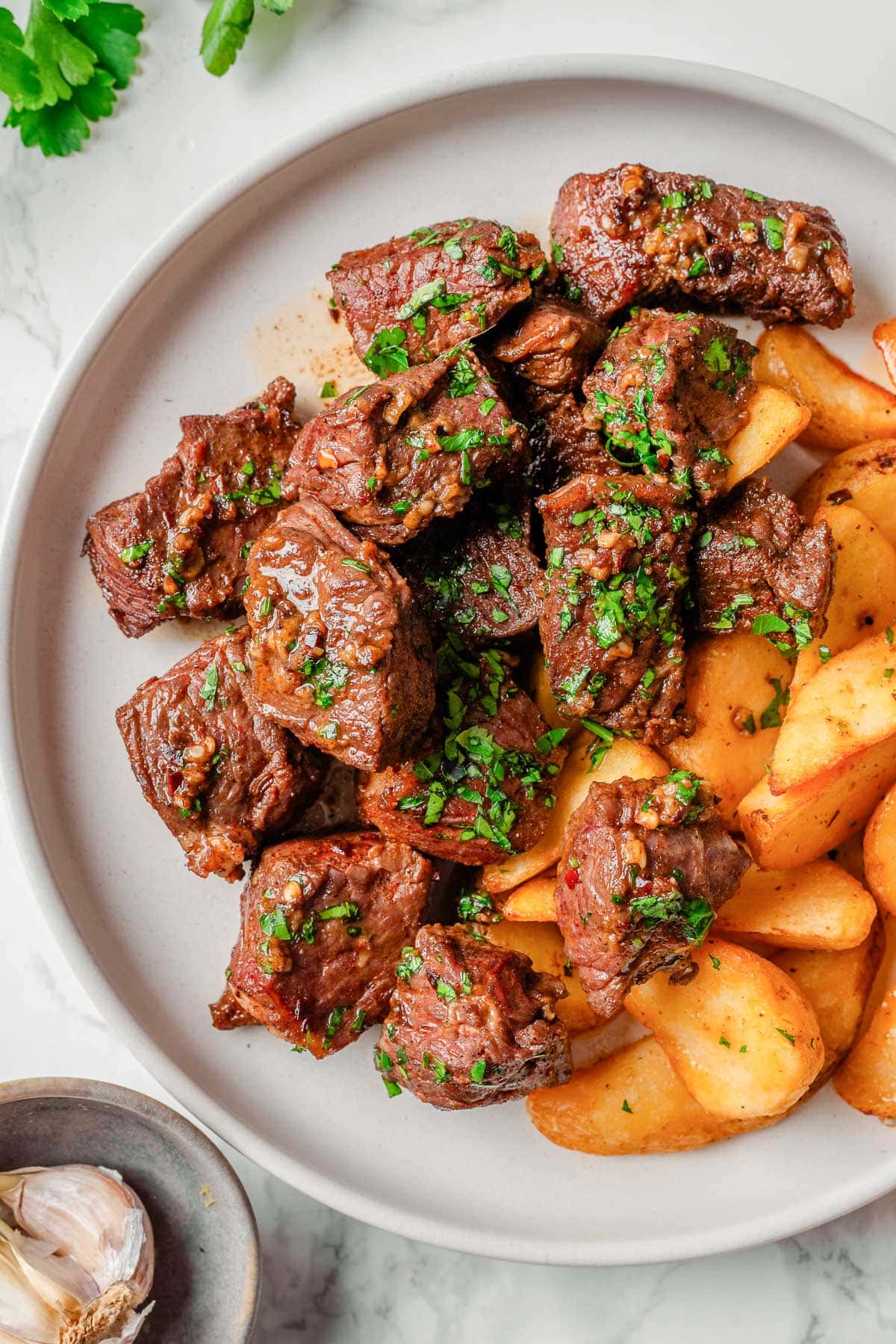 Garlic butter steak bites with potatoes on a plate.