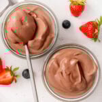 Cottage cheese chocolate mousse in glass jars with a spoon. Berries on a plate.