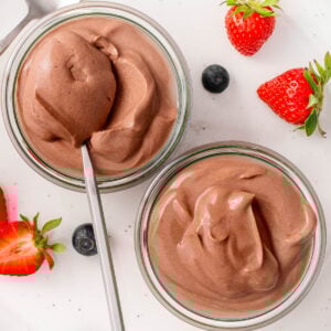 Cottage cheese chocolate mousse in glass jars with a spoon. Berries on a plate.