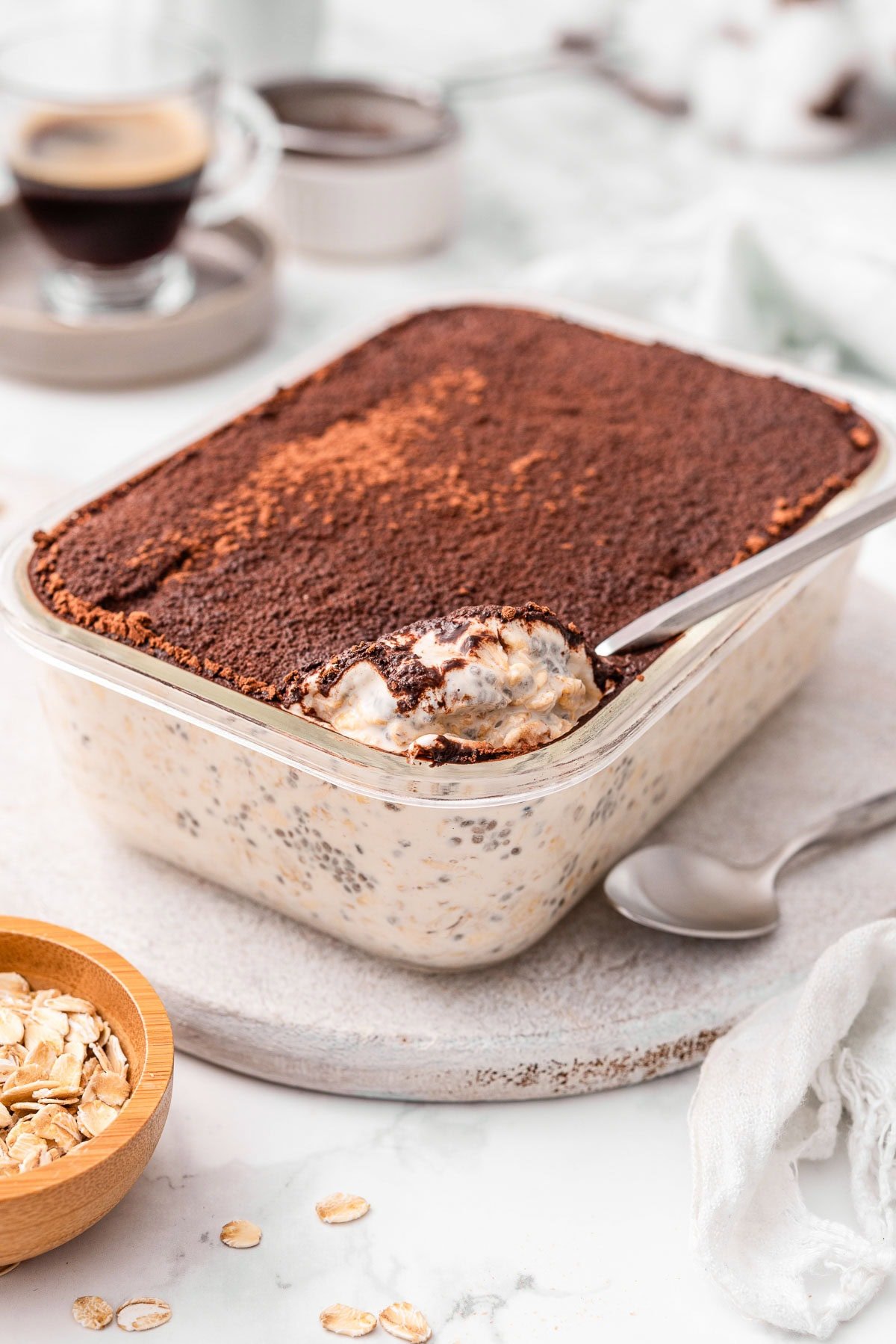 Tiramisu overnight oats in glass container with a spoon.
