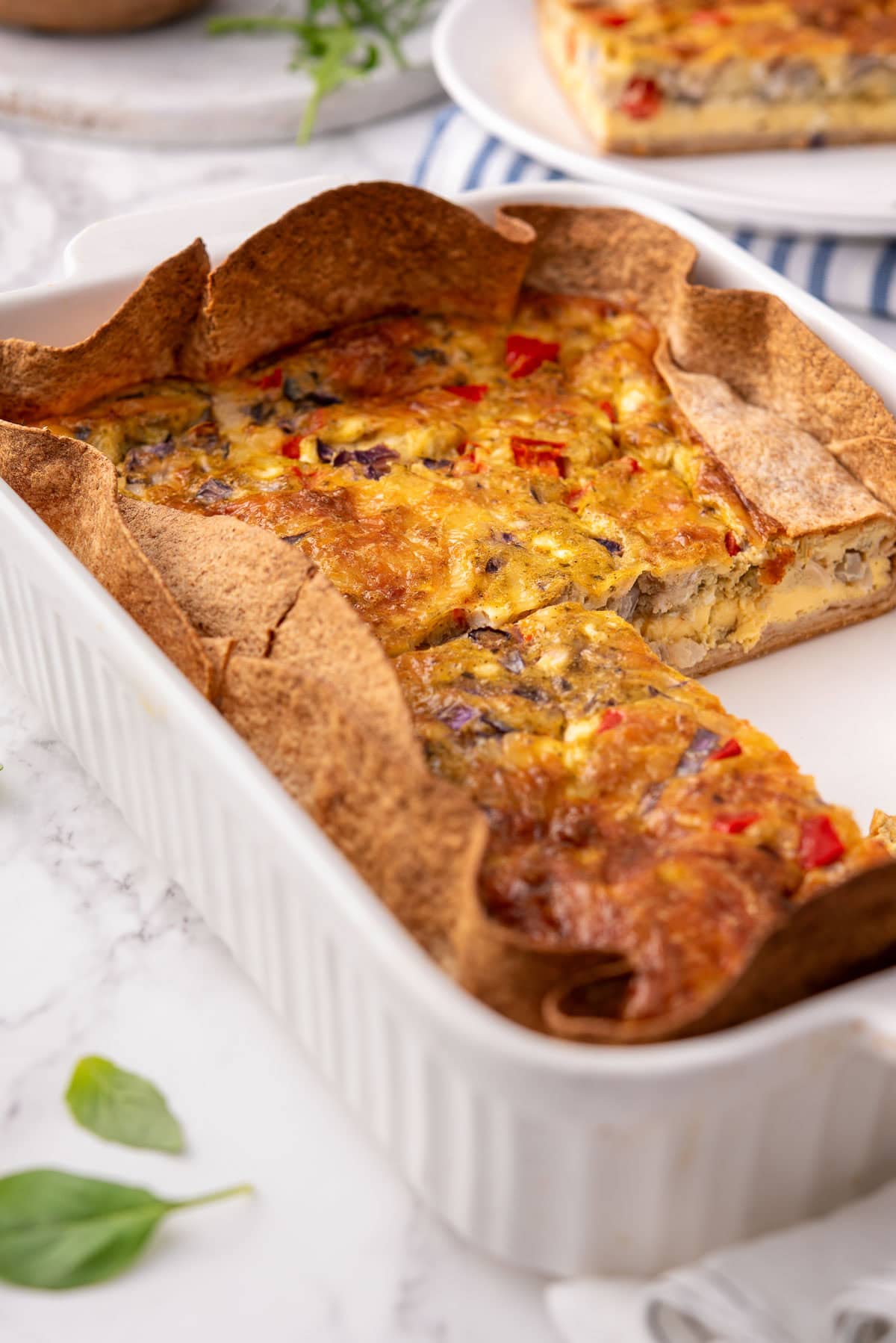 Tortilla quiche bake sliced in a baking dish.