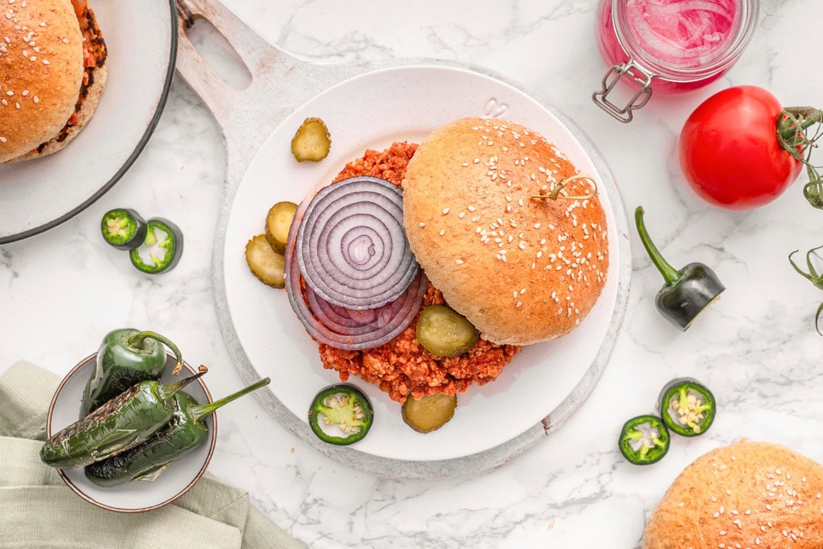Looking down on a plate with turkey sloppy joes garnished with red onion, pickles and jalapenos.