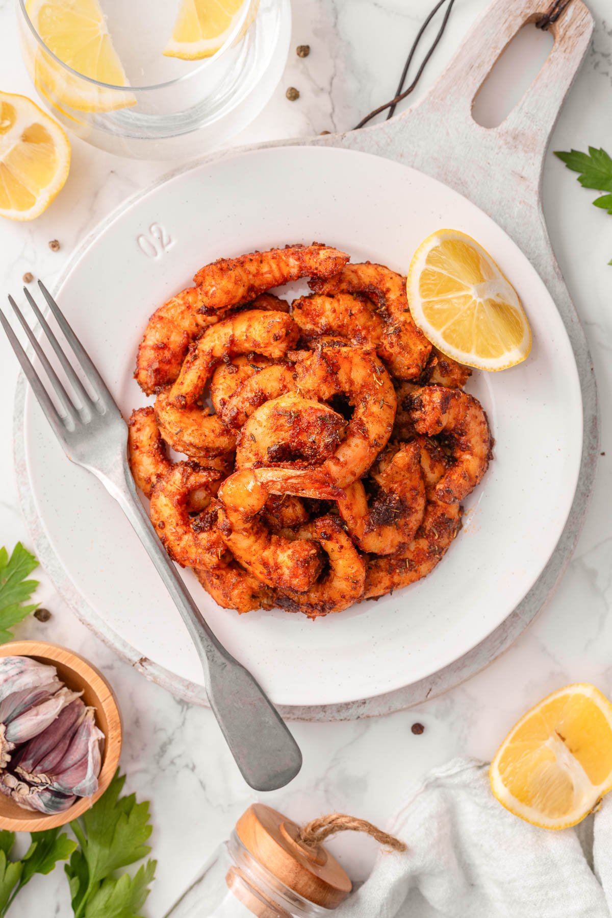 Looking down on a bowl with cajun shrimp, lemon and fork.