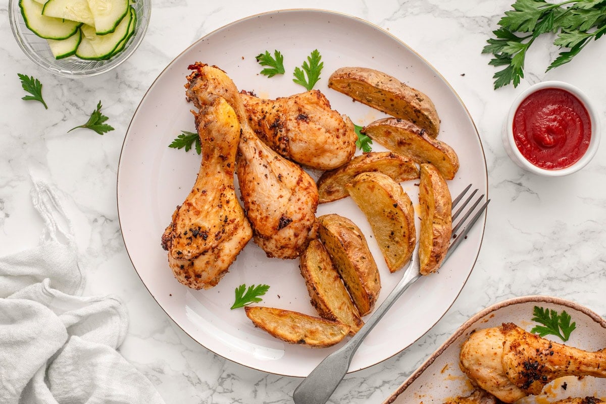Baked chicken drumsticks served with potato wedges.