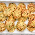 Cottage cheese zucchini fritters on a baking sheet lined with paper towels.