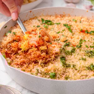 Chicken parmesan zucchini skillet in a pan with person holding a spoon of it.