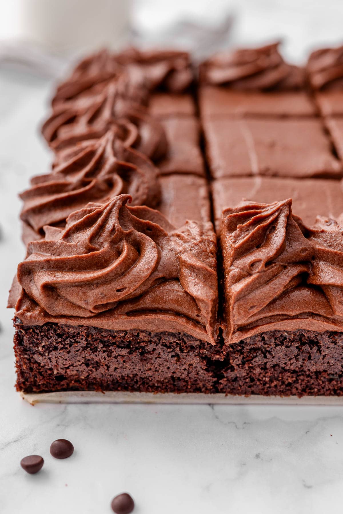 Side view of frosted and sliced healthy chocolate zucchini cake.