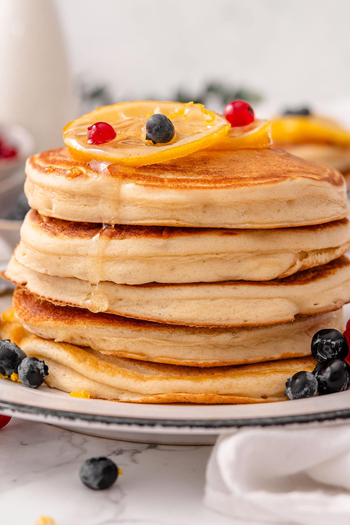 Greek yogurt pancakes stack with lemon and berries on top.