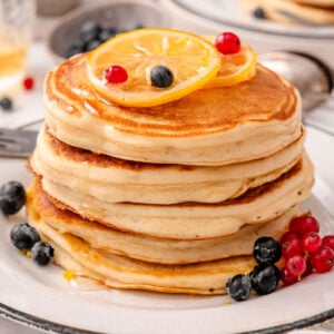 Greek yogurt pancakes stack with lemon and berries on top.