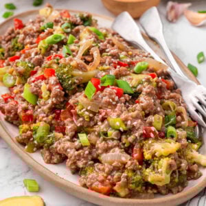 Ground beef stir fry garnished with sesame seeds and green onion on a platter.
