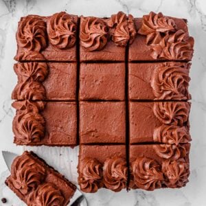 Healthy chocolate zucchini cake on a counter with one slice served.